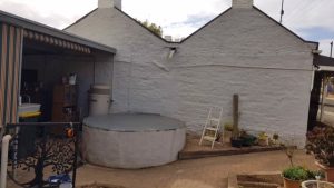 White base for rainwater tank on side of cottage in Kapunda SA