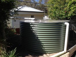 olive green rainwater tank behind house