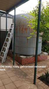 galvanised rainwater tank with ladder next to it.