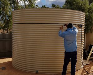 Steve completing a rainwater tank using a tool to join the sections together