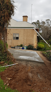 concrete base for rainwater tank with cream house in background